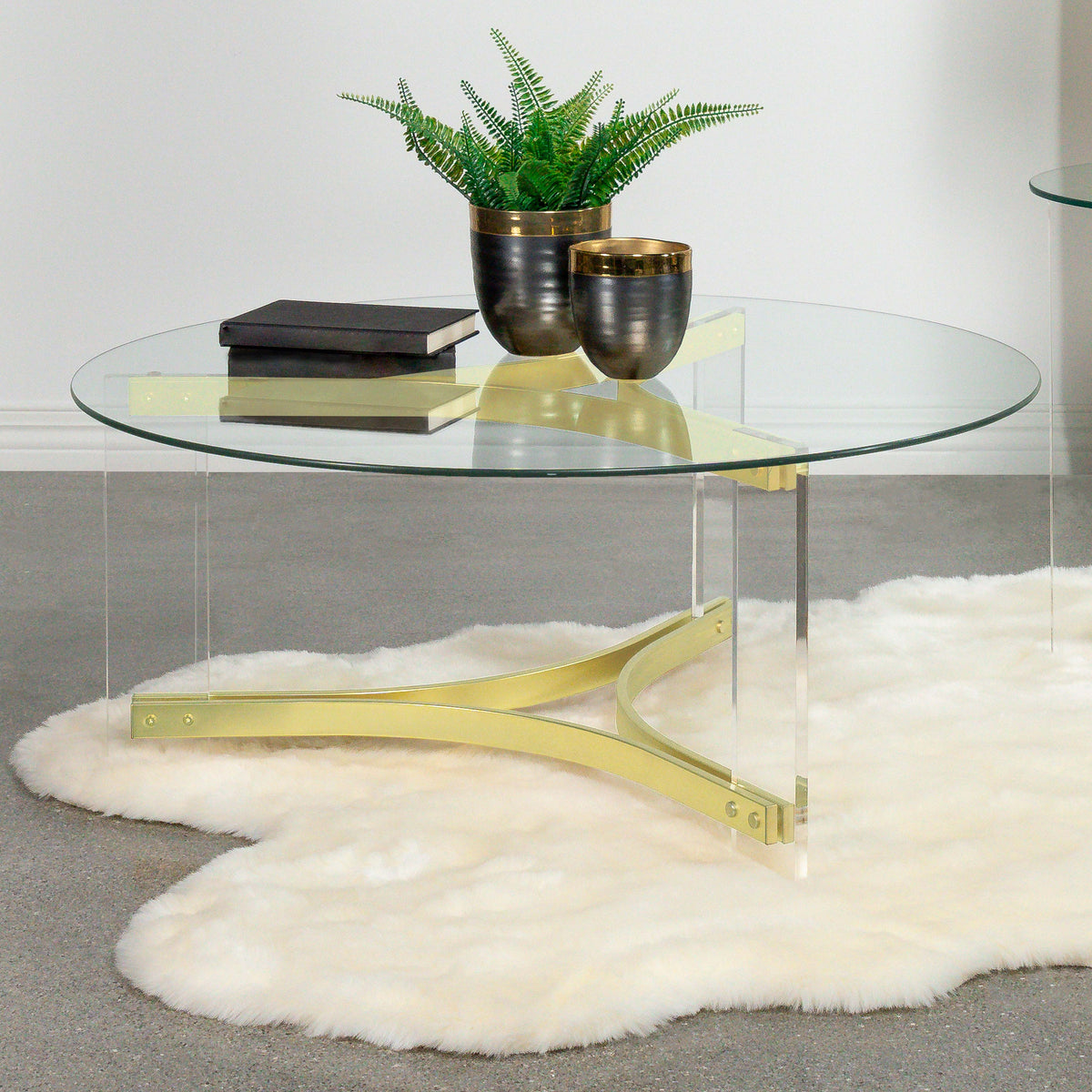 Mesa de centro Janessa redonda con tapa de vidrio y patas acrílicas, latón mate