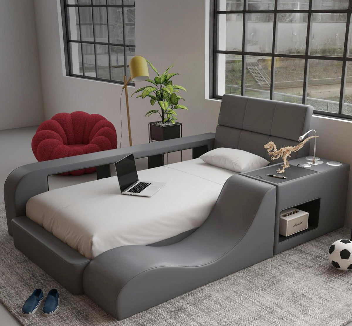 Kids twin bed in gray faux leather with a paneled headboard, curved wave-shaped side lounger, side rail, and built-in side console with a flexible reading lamp and open storage cubby, styled in a bright loft bedroom with a red accent chair and a soccer ball.