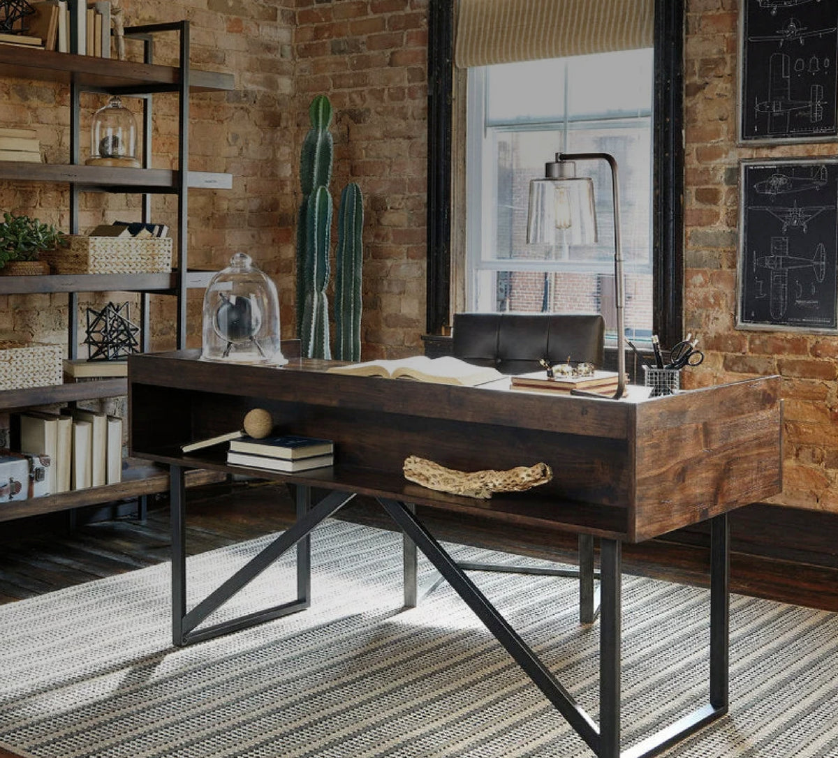 Rustic brown wood desk with open shelf and black metal X-frame base in an industrial-style home office.