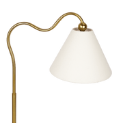 Lámpara de mesa curva con base de anillo de latón ornamentado y pantalla triangular blanca.